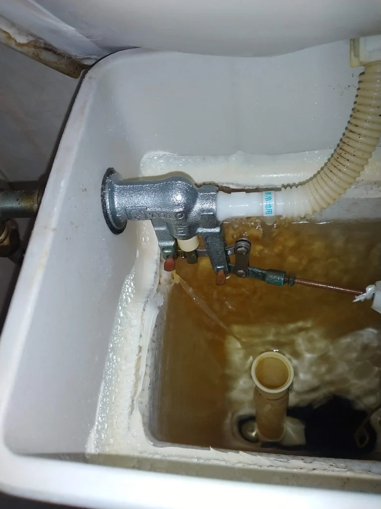 リフォーム前:タンクから水が流れ続けるトイレの状態