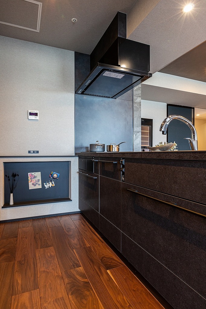 リノベーション後:ニッチ収納とマグネットパネルを備えた対面キッチン横の収納スペース