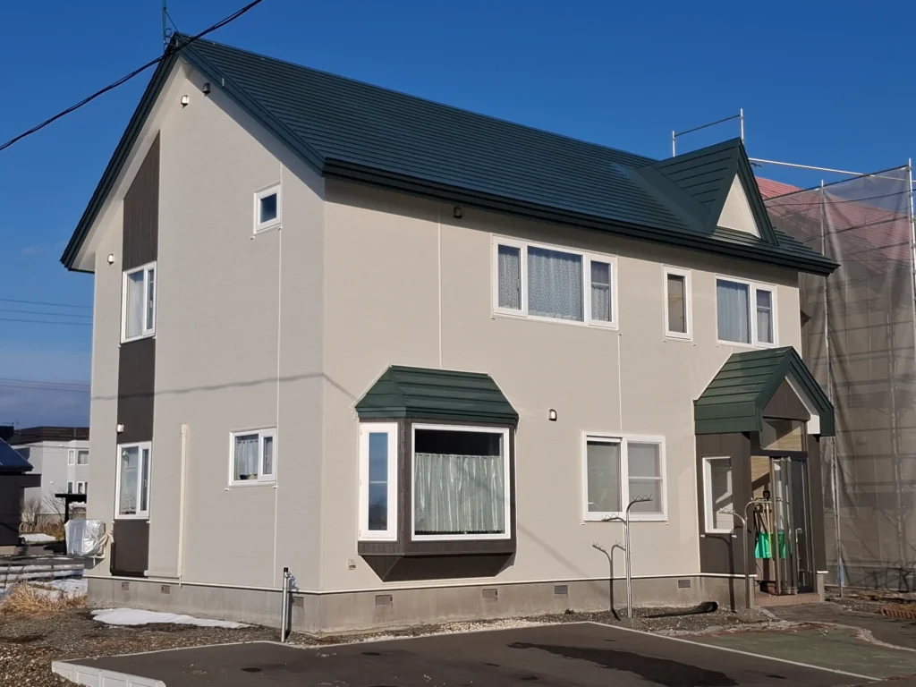 リフォーム後：白い金属サイディングに木目アクセントを施した外壁