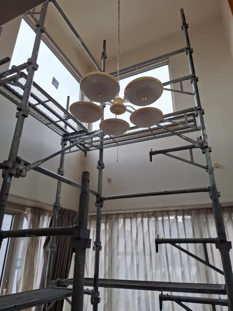 施工中：職人が吹抜け窓のガラスを丁寧に取り付けている様子