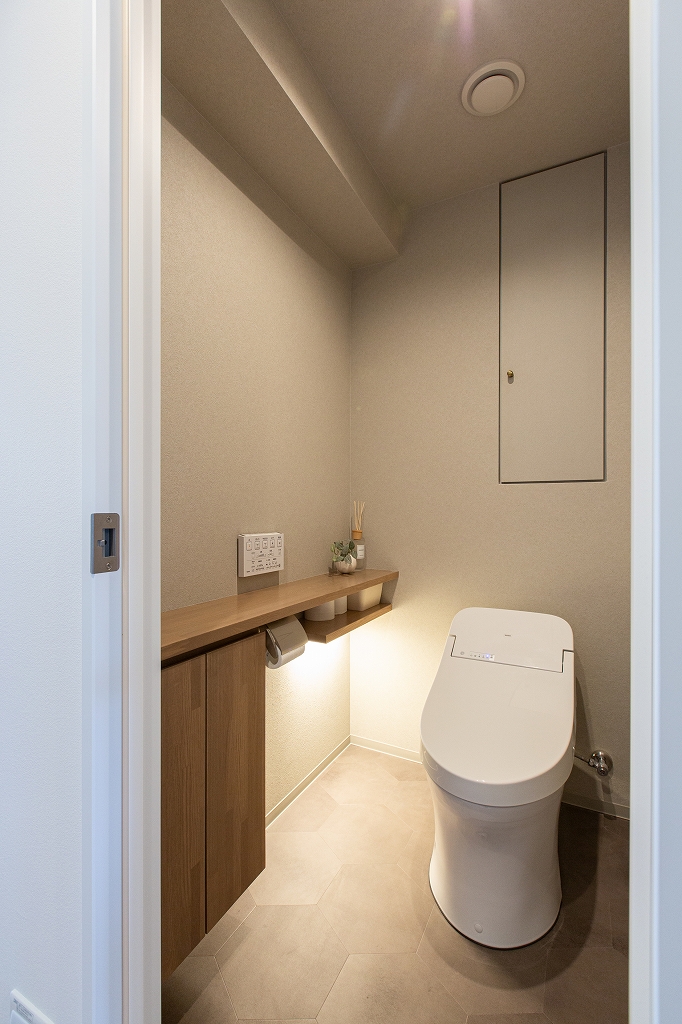 リノベーション後：落ち着いたトイレ空間。グレー系のクロスでまとめた。カウンターは造作。塗装仕上げ。