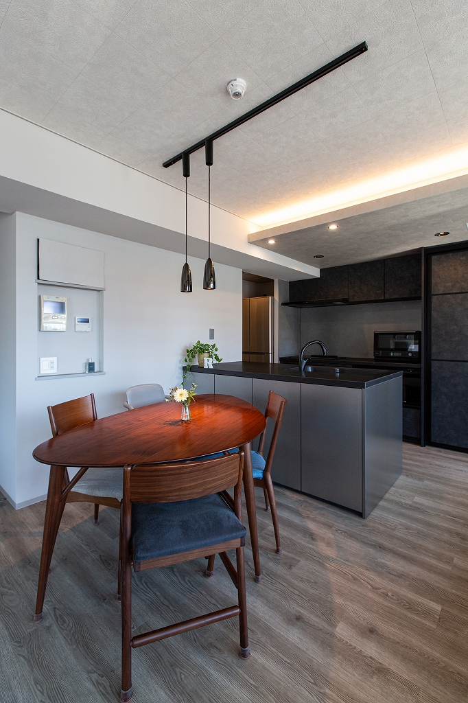 リノベーション後：グレーでまとめたダイニングスペース、天井に間接照明、壁にはリモコン用のニッチ